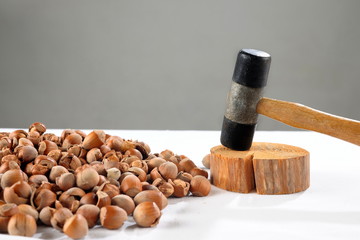 Crack hazelnuts with a hammer on the white table
