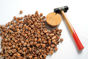 Crack hazelnuts with a hammer on the white table