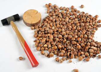 Crack hazelnuts with a hammer on the white table
