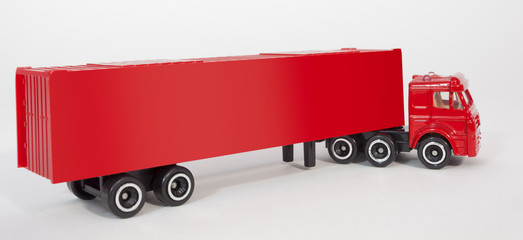 Red plastic toy semi truck cab with trailer container. Isolated.