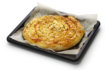 homemade kol borek, turkish savoury rounded pie on oven tray isolated on white background