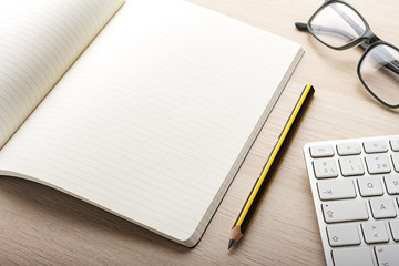 notebook and pen on top of wooden desk with computer