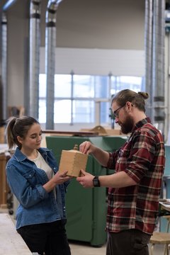 Male and female carpenters examining a piece of wooden furniture