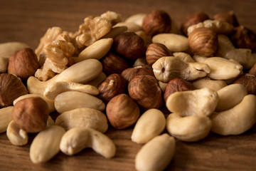nuts, in a white bowl, fried on a dark wood background, mixture of walnuts, almonds and roasted nuts, top view