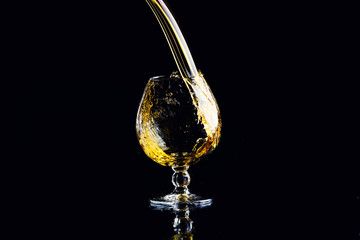 glass with cognac with splash on a black background
