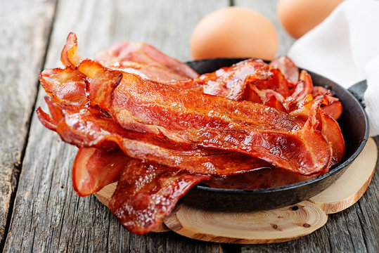 Hot fried bacon pieces in a cast iron skillet.top view