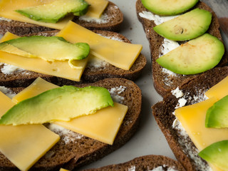 Sandwiches of avocado and cheese on black bread