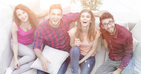 Obraz premium four happy friends laughing while sitting on the couch