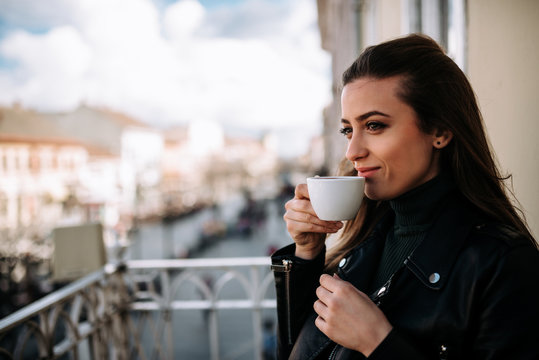 Close-up image of woman drinking cup of coffee on the terrace.