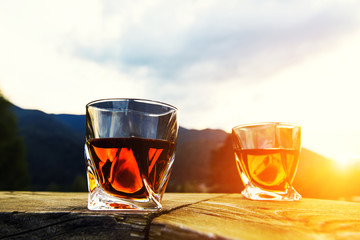 shot of whiskey at sunset dramatic sky on mountain landscape background