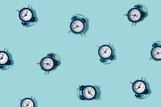 Flat lay retro beautiful new alarm clock on blue color background. Pattern. Top