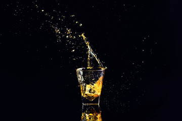 Isolated shot of whiskey with splash on black background, brandy in a glass