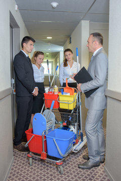 Supervisor with cleaning staff in hotel corridor