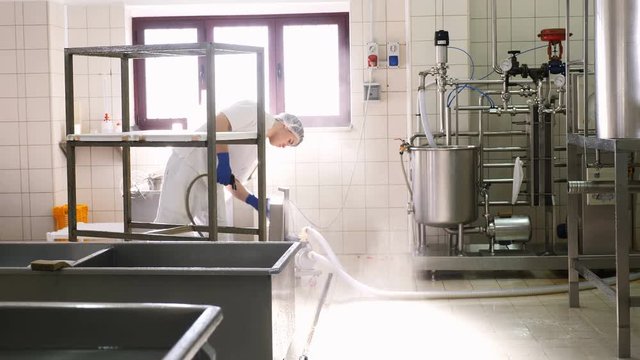 operator cleaning the dairy cheese factory with water pump