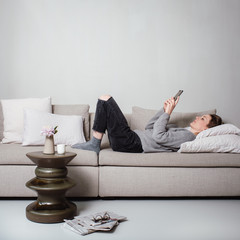 frau liegt auf dem sofa und schreibt nachricht mit ihrem telefon