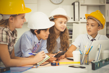 Teens engineers discussing draft at the table