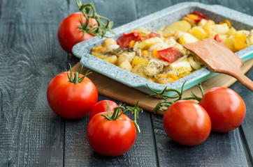 stewed potatoes and ripe tomatoes on a wooden background