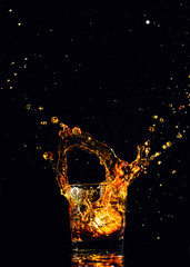 Isolated shot of whiskey with splash on black background, brandy in a glass