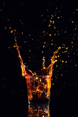 Isolated shot of whiskey with splash on black background, brandy in a glass
