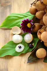 Bunch of longans and peeled fruits on wooden background