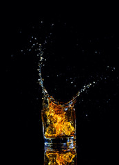 Isolated shot of whiskey with splash on black background, brandy in a glass