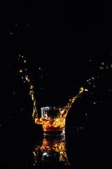 Isolated shot of whiskey with splash on black background, brandy in a glass