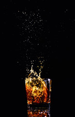 Isolated shot of whiskey with splash on black background, brandy in a glass