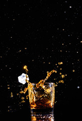 Isolated shot of whiskey with splash on black background, brandy in a glass