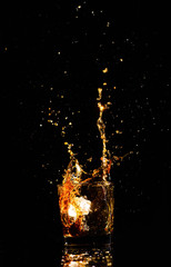 Isolated shot of whiskey with splash on black background, brandy in a glass