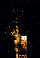 Isolated shot of whiskey with splash on black background, brandy in a glass