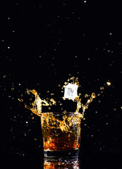 Isolated shot of whiskey with splash on black background, brandy in a glass