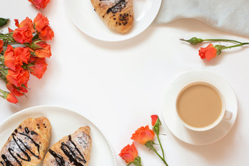 Freshly baked chocolate croissants and cup of coffee on white. Top view. Female spring breakfast concept. Copy space.
