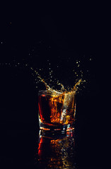 Isolated shot of whiskey with splash on black background, brandy in a glass