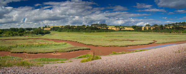 Fototapeta na wymiar Panorama of a picturesque place on the shore of an English channel - Budleigh Salterton. Sunny summer day. Clouds in the blue sky. Devon. England