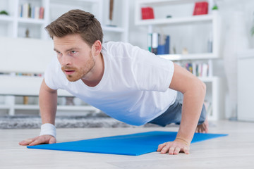 young fit guy doing push ups in the living room