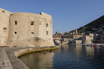 Fototapeta na wymiar The mighty city wall of Dubrovnik in the morning light and in the background the boat harbor