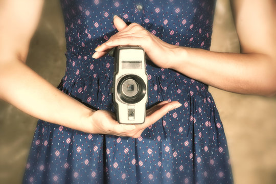 silhouette of a girl in a blue dress with an old camera in her hand