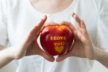 apple with the inscription "I love you" in the hands of a girl
