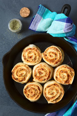 Homemade pizza rolls or pinwheels filled with ham, onion, tomato sauce and cheese, photographed overhead on slate with natural light (Selective Focus, Focus on the top of the rolls)