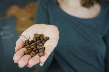 Granos de café tostado de importación en la mano de una mujer 