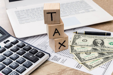 Obraz premium tax form with dollar, calculator and wooden cubes with text TAX