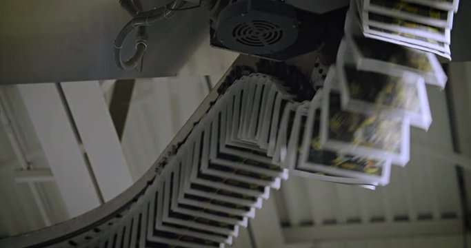 Newspapers move along an overhead conveyor belt at a newspaper factory.