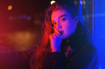 Sexy young woman posing over night city dramatic neon background