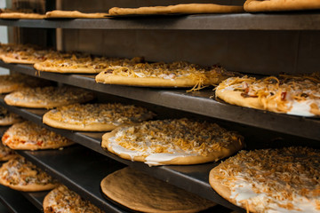 A lot of pizza on the shelves. Pizza before baking