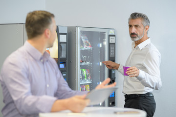 man taking coffee from vending machine - obrazy, fototapety, plakaty