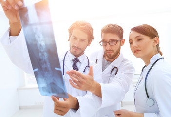 Three confident doctors examine an x-ray