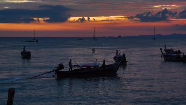 Silhouettes of a group of a long-tail boats moored on the coast at sunset