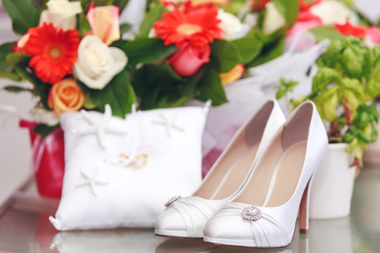 Gorgeous bride shoes decorated with crystals on floral background. Beautiful white shoes encrusted with crystals, isolated on decorative background. Best picture of women shoes for wedding projects.