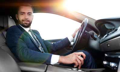 View from the side confident businessman sits at the wheel of a car