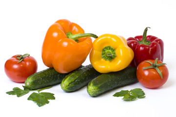 Red yellow and orange peppers with tomatoes on a white background. Cucumbers with colorful peppers in composition on a white background